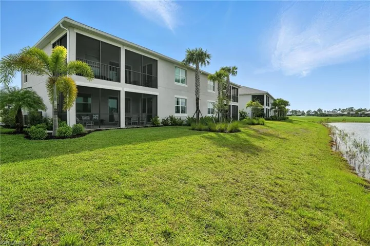 Rear view of property with stucco siding, a lawn, and a water view