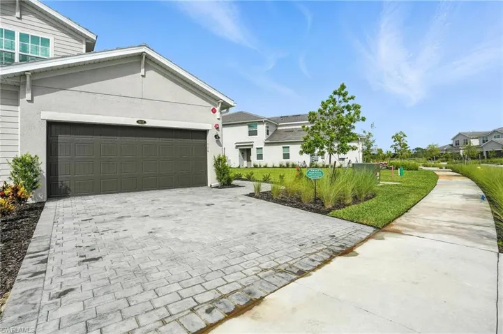 View of front facade with decorative driveway, an attached garage, and stucco siding