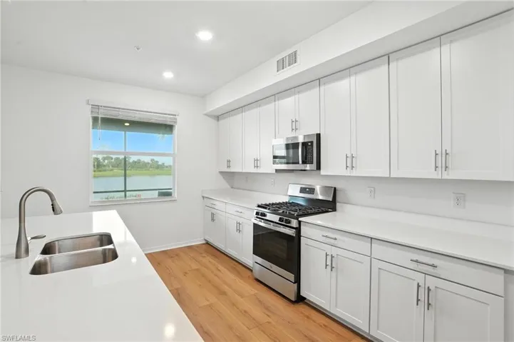 Kitchen featuring appliances with stainless steel finishes, light wood finished floors, light countertops, recessed lighting, and white cabinetry