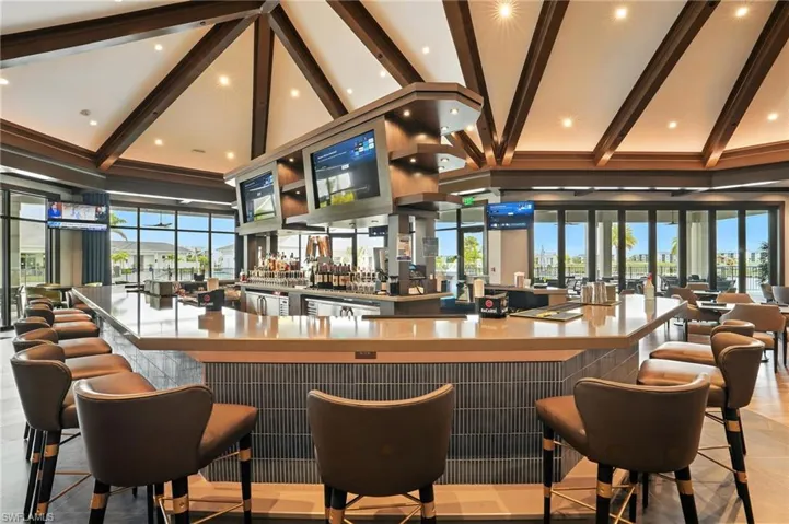 Community bar area featuring beam ceiling, high vaulted ceiling, and plenty of natural light