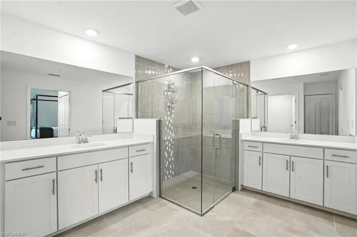 Bathroom with two vanities, a stall shower, and recessed lighting