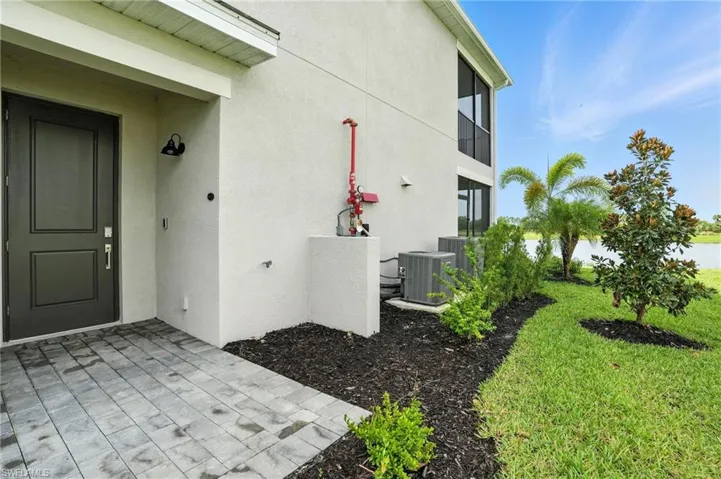 Property entrance with stucco siding, a lawn, and a patio