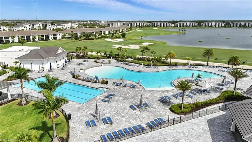 Community pool featuring view of golf course and a patio