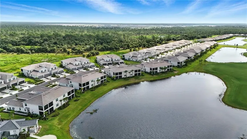 Aerial perspective of suburban area with a nearby body of water and a forest