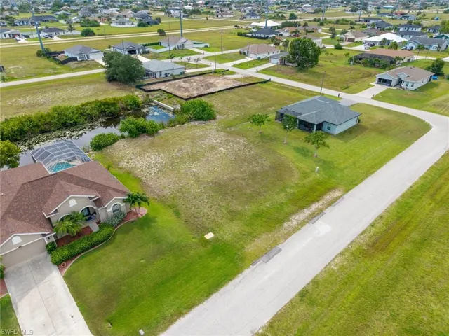 Expansive residential lot featuring a cleared building site, mature green landscaping, and frontage along a paved road