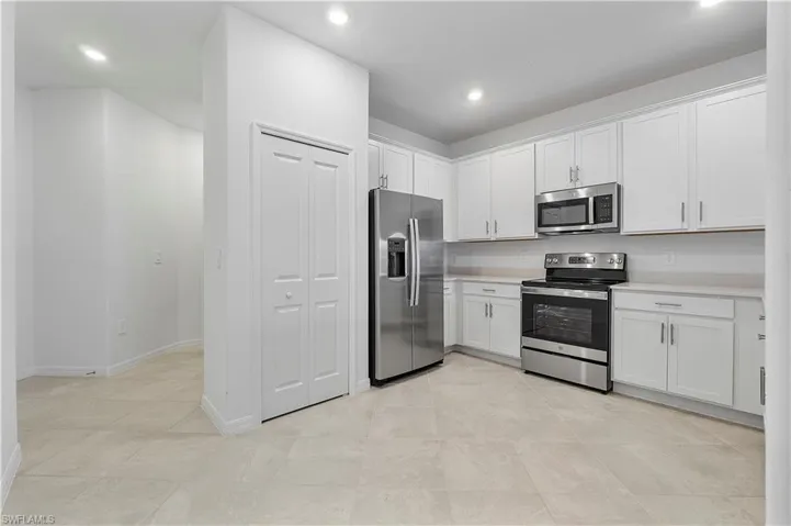 Kitchen featuring light tile flooring, white cabinetry, and appliances with stainless steel finishes