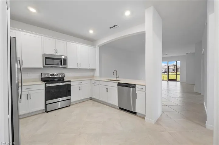 Kitchen with sink, light tile floors, white cabinetry, and appliances with stainless steel finishes