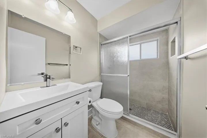 Second Unit-Full bathroom featuring vanity, a shower stall, and light tile patterned floors