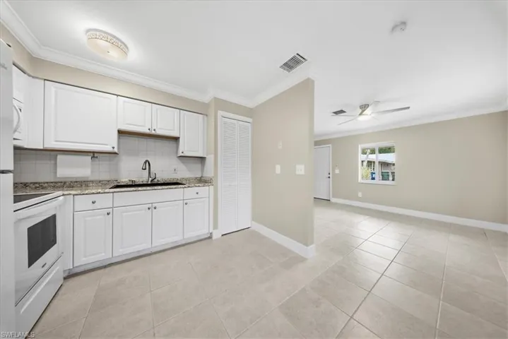 Second Unit-Kitchen with white cabinets, light tile patterned floors, electric stove, crown molding, and light stone counters