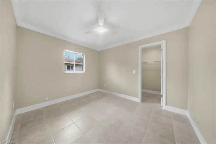 Second Unit-Unfurnished bedroom featuring a spacious closet, crown molding, a ceiling fan, and light tile patterned floors