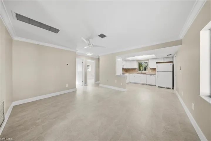 Unfurnished living room with ceiling fan and crown molding