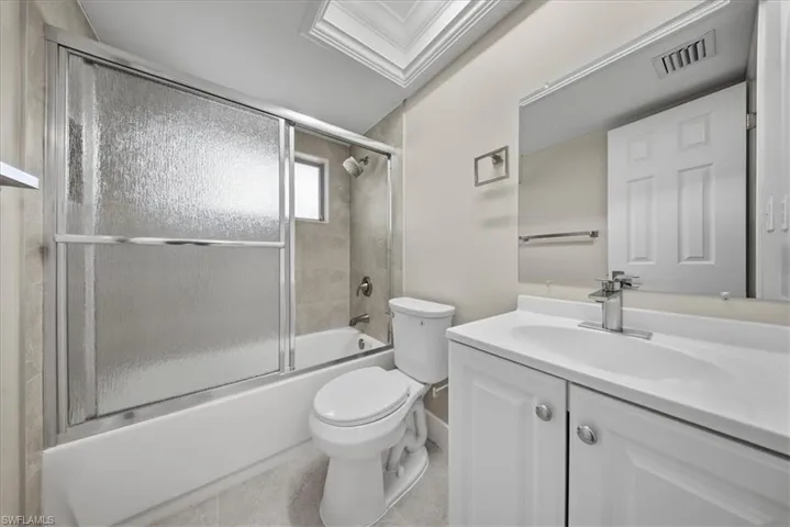 Bathroom featuring vanity, shower / bath combination with glass door, and light tile patterned floors