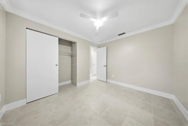 Second Unit-Unfurnished bedroom featuring ornamental molding, a closet, ceiling fan, and light tile patterned floors
