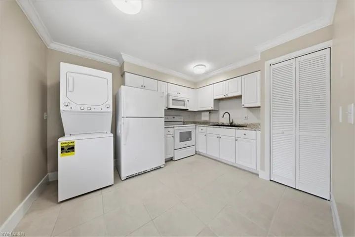 Second Unit white cabinetry, stacked washer and clothes dryer, light tile patterned floors, and light countertops