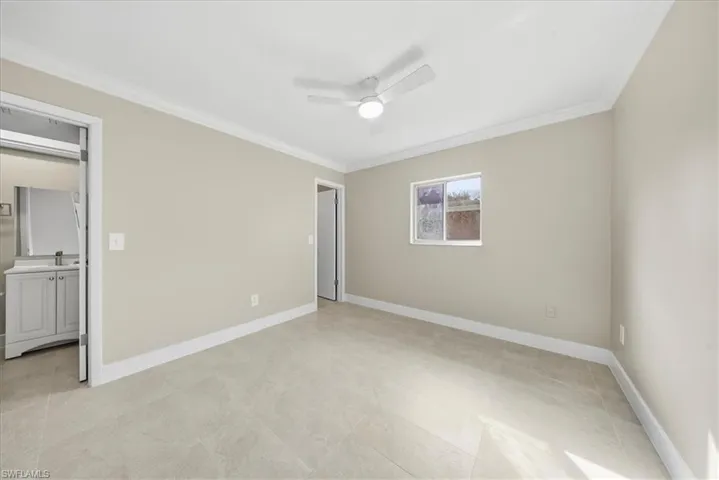 Unfurnished bedroom featuring crown molding, ceiling fan, and ensuite bath