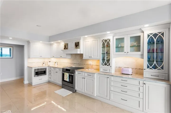 Recessed and under cabinet lighting, glass custom cabinetry, and beautiful counters