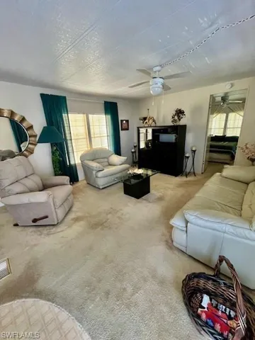 Carpeted living area featuring a ceiling fan, a healthy amount of natural light, and fully furnished