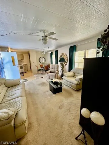 Carpeted living area featuring ceiling fan