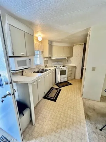 Kitchen with white appliances, light countertops, a textured ceiling, and light floors