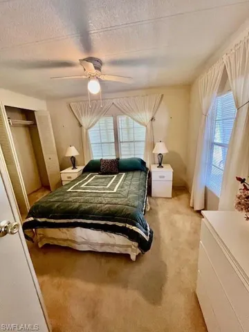 Bedroom featuring light carpet, a ceiling fan, and a textured ceiling
