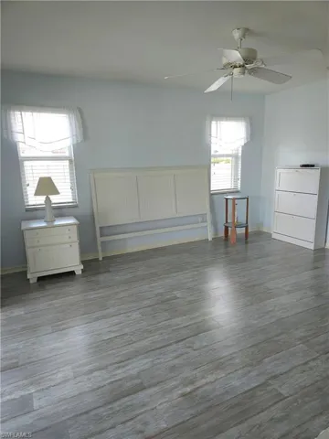 Primary bedroom with room for a king-sized bed features light wood-style laminated plank floors, ceiling fan and sliders to the lanai.