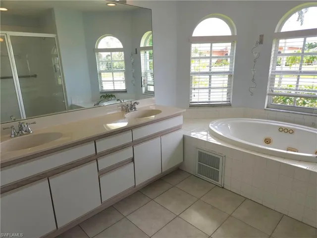 Bathroom featuring independent shower and bath, dual sinks and vanity.