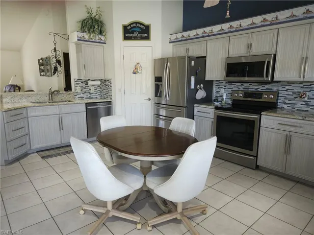 Kitchen with appliances with stainless steel finishes, gray cabinetry, decorative backsplash, and sink