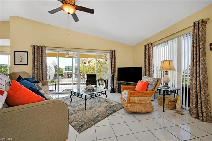 Living room featuring lofted ceiling, light tile patterned floors, and ceiling fan