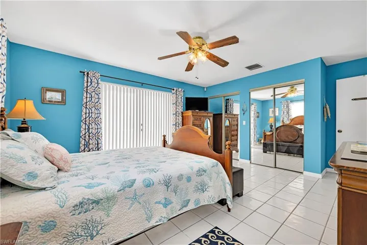 Bedroom featuring multiple closets, ceiling fan, and light tile patterned floors