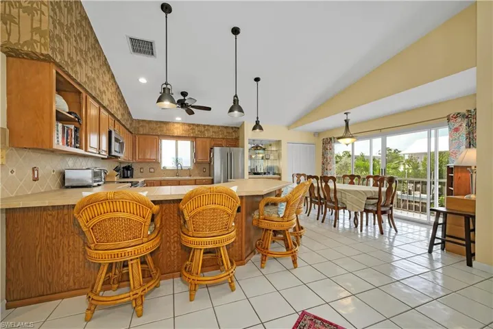 Kitchen featuring kitchen peninsula, stainless steel appliances, lofted ceiling, and ceiling fan