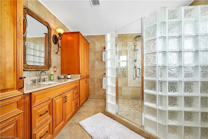 Bathroom with vanity, tile walls, tile patterned floors, and a shower with shower door