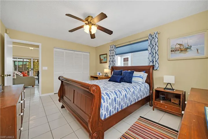 Tiled bedroom featuring a textured ceiling, ceiling fan, and a closet