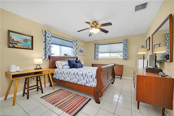 Bedroom with a textured ceiling, multiple windows, ceiling fan, and light tile patterned floors