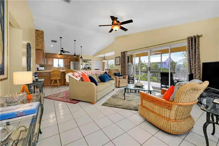 Living room with ceiling fan, vaulted ceiling, and light tile patterned flooring