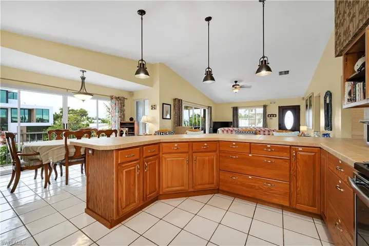 Kitchen featuring pendant lighting, kitchen peninsula, vaulted ceiling, and ceiling fan