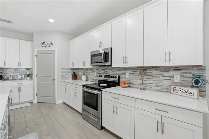 Kitchen with stainless steel appliances, white cabinetry, light wood finished floors, and recessed lighting