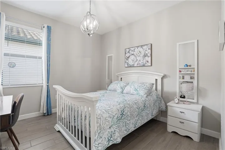 Bedroom with wood finished floors and suspended lighting