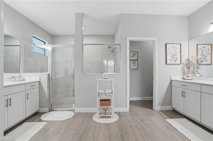 Full bathroom with vanity, a stall shower, and light wood finished floors