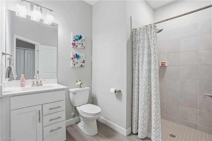 Full bath with vanity, a shower stall, and light wood-style floors