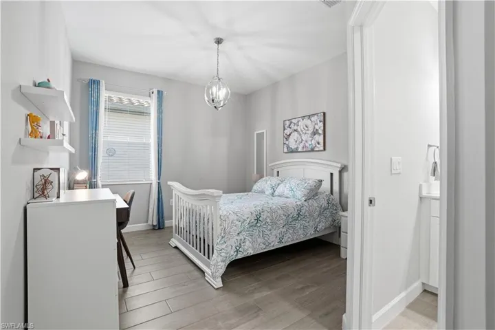 Bedroom with light wood-style floors and hanging lights