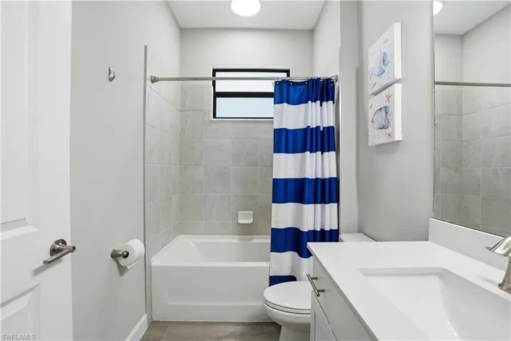 Bathroom with vanity, shower / bath combo with shower curtain, and light wood finished floors