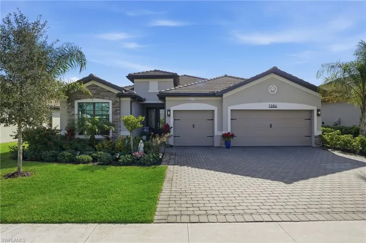 View of front of property featuring stone siding, an attached garage, decorative driveway, stucco siding, and a front lawn