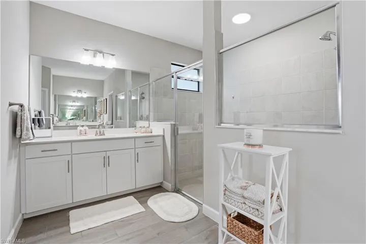 Bathroom with vanity, a stall shower, and light wood-style floors