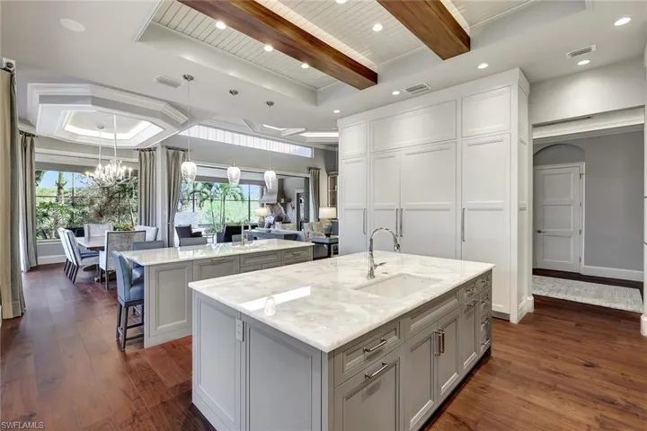 Kitchen featuring a healthy amount of sunlight, dark hardwood / wood-style flooring, sink, and a large island with sink