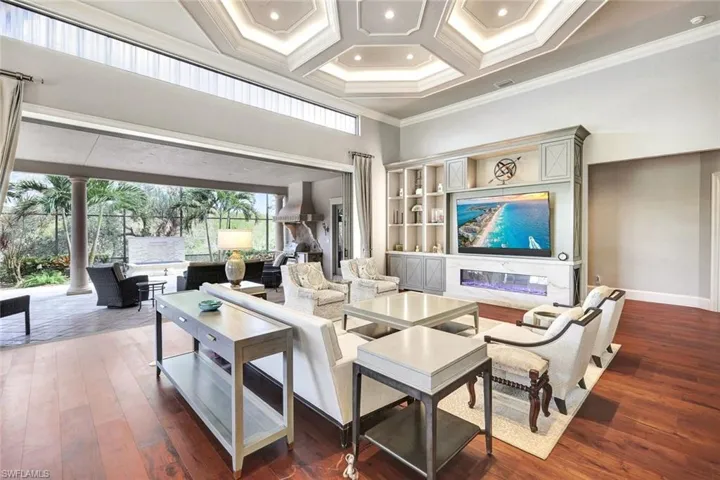 Living room with ornamental molding, decorative columns, dark wood-type flooring, and coffered ceiling