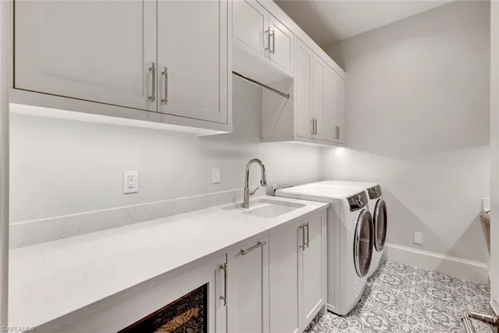 Laundry room featuring cabinets, independent washer and dryer, sink, and light tile patterned floors