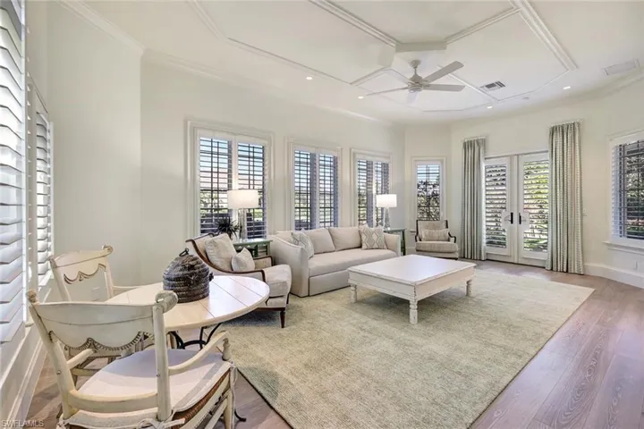Living room with a wealth of natural light, light hardwood / wood-style flooring, ceiling fan, and ornamental molding