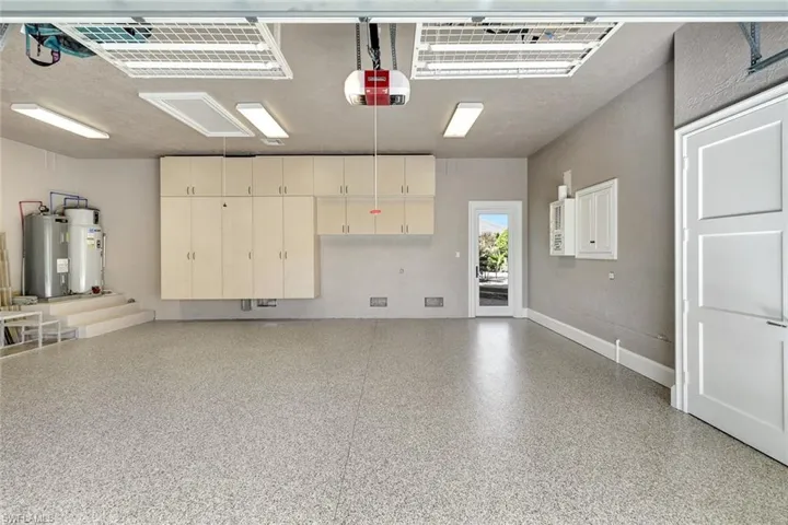 Garage featuring electric water heater, a garage door opener, and gas water heater