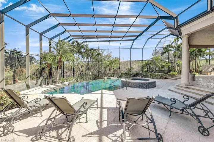 View of swimming pool with glass enclosure, a patio area, and an in ground hot tub