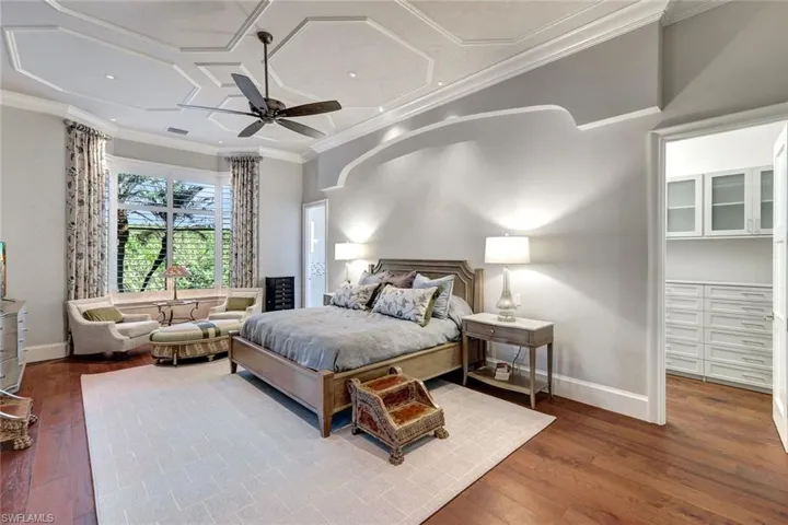 Bedroom with hardwood / wood-style flooring, ceiling fan, crown molding, and coffered ceiling